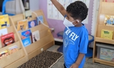 Young boy raising his hand in the classroom